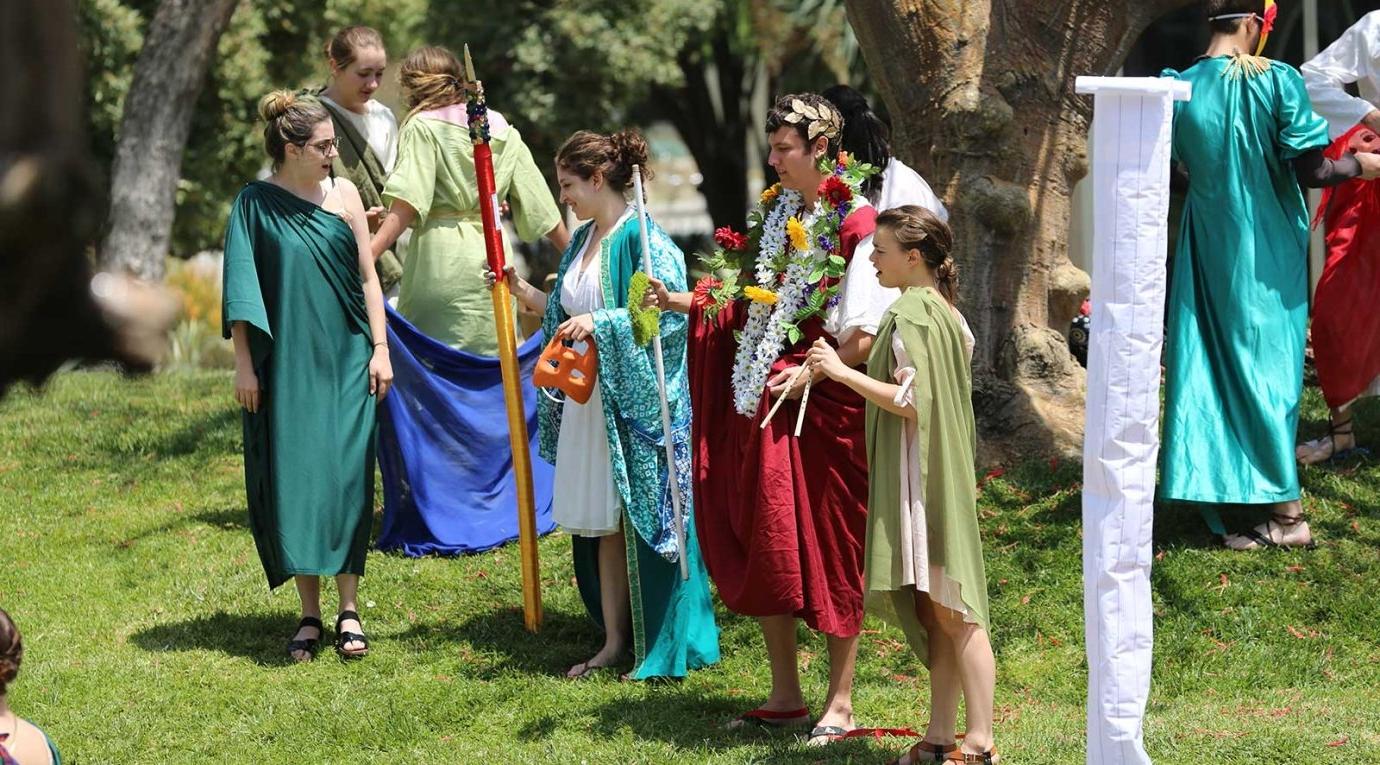 classics students perform a play in togas on the mounds