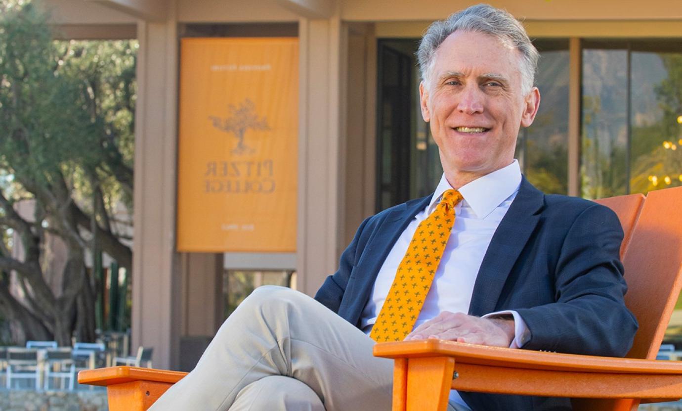 strom thacker sits in an orange wooden chair in front of McConnell Center