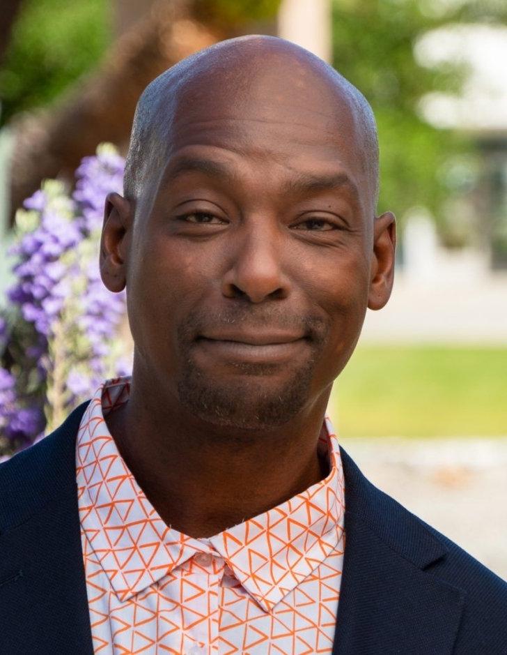 Portrait of Kenneth Butler in front of purple flowers. 