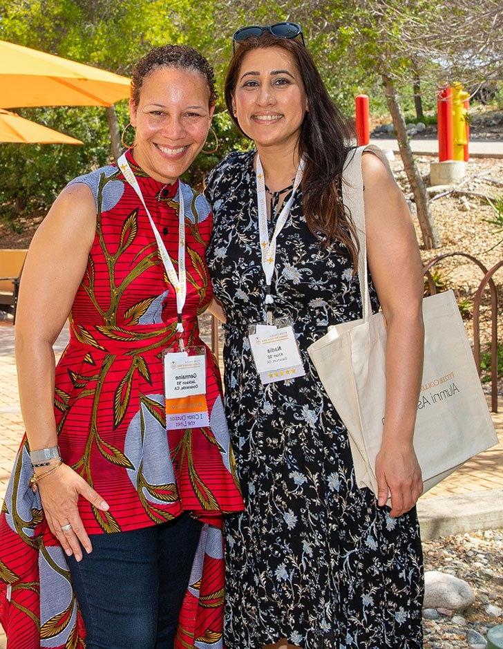 two alums pose at the first gen mixer outside the media studies building