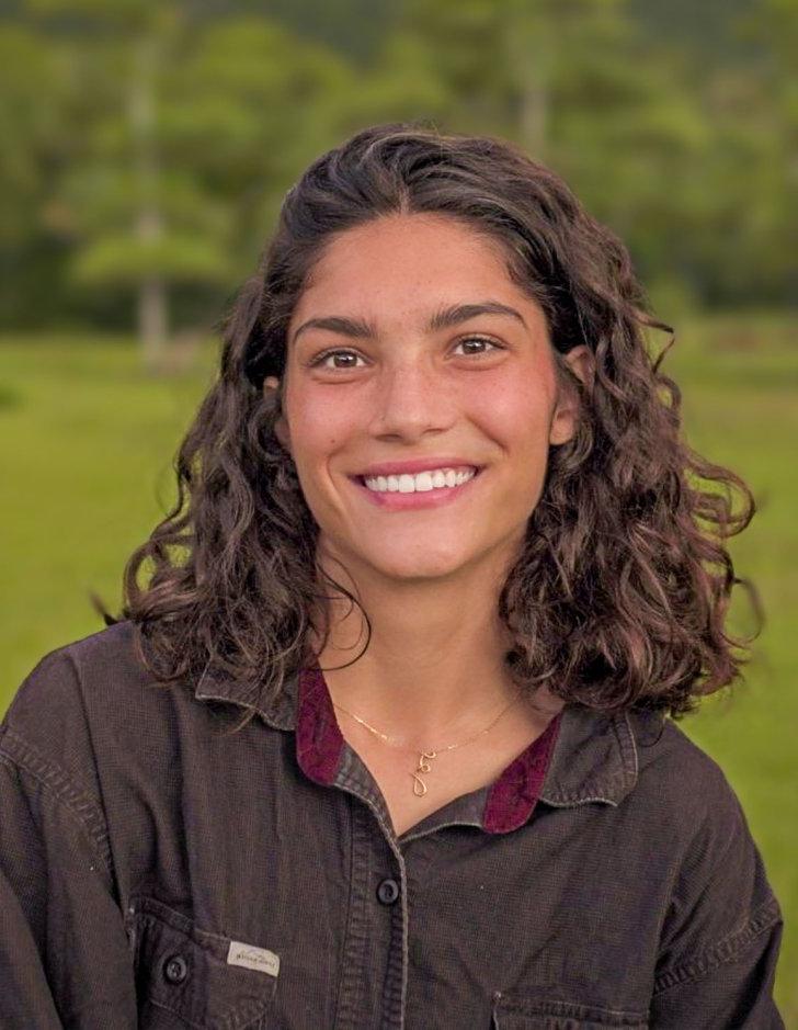 Zhane Moledina poses outside in front of a green landscape