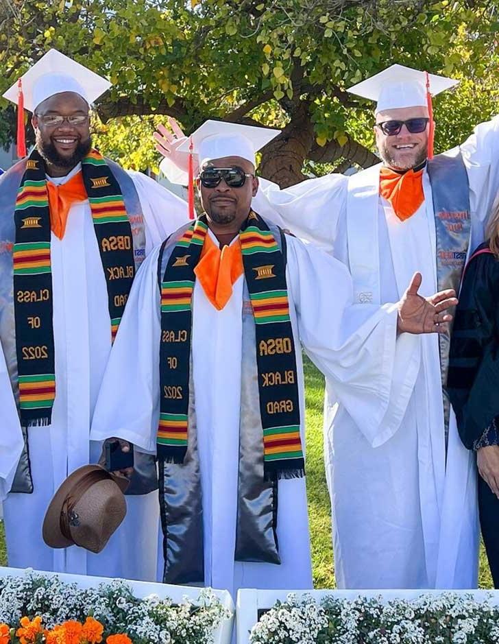 three inside-out graduates celebrate in caps and gowns on the pitzer mounds